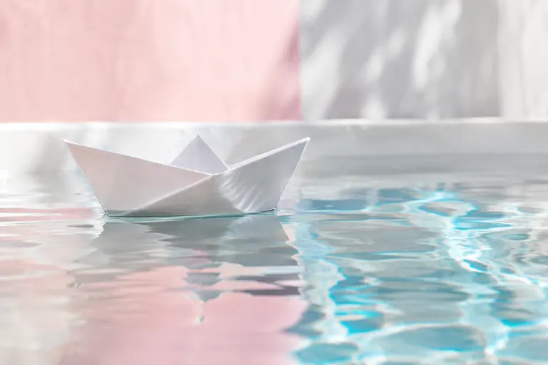 Bateau en papier blanc flottant sur une eau claire, image de la ligne de flottaison